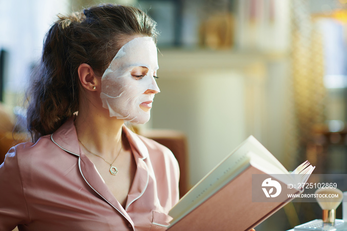 modern housewife with facial mask reading book