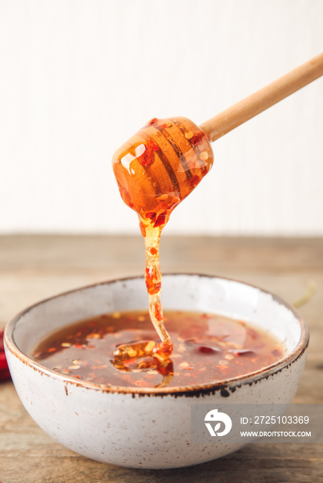 将热蜂蜜从勺子倒入木桌上的碗中