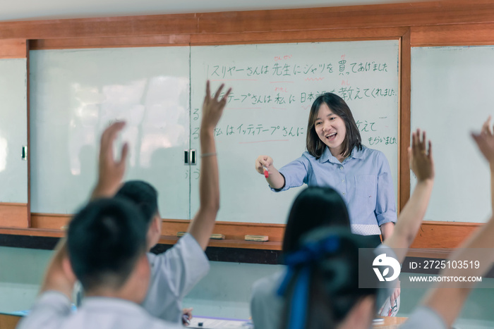 An Asian female teacher is teaching Japanese. The meaning of texts are  Mr. Suriya bought a shirt fo