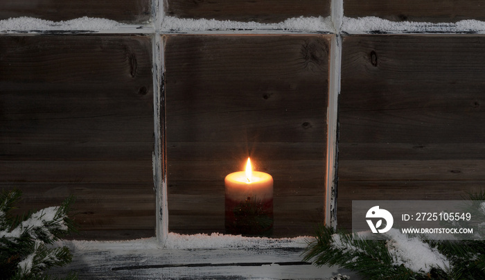 飘雪的窗户和带发光蜡烛的冷杉树枝