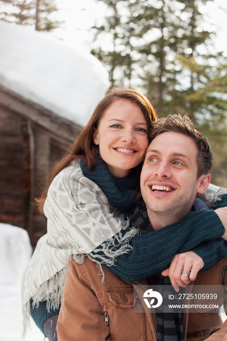 Portrait happy affectionate couple hugging outside snowy cabin