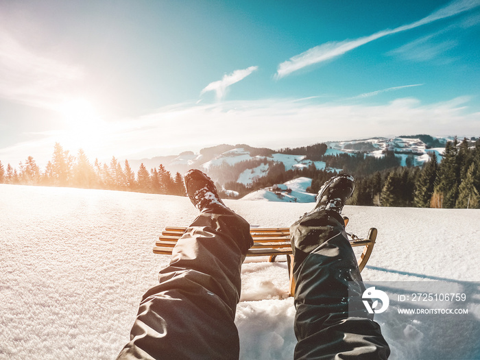 Pov view of young man looking the sunset on snow high mountains with vintage wood sledding