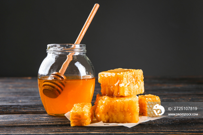 Aromatic honey in jar and honeycombs on wooden table