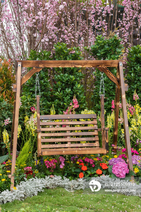 Wooden swing seat in backyard flower garden