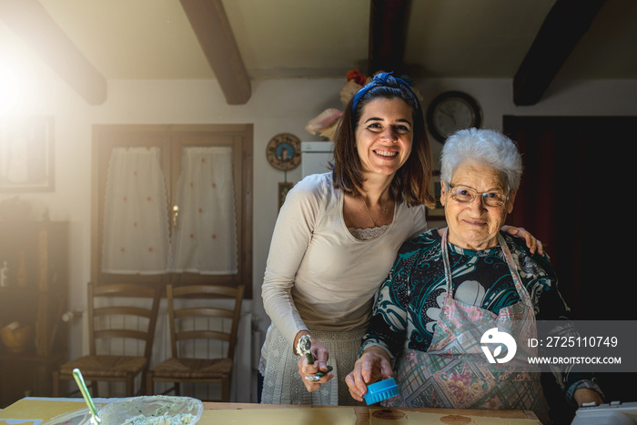 Portrait of caucasian grandmother and granddaughter smiling while learning to prepare dough for maki