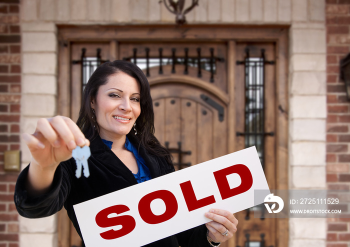 Hispanic Woman Holding Sold Sign and Keys In Front of House