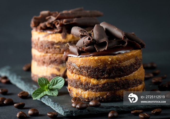 Chocolate cakes on black slatter board with mint, coffee beans on dark background, closeup photo. Fr