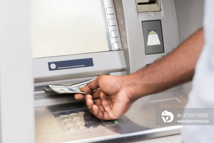 Unrecognizable young african man getting money from ATM