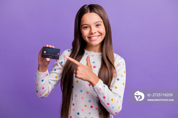 Photo portrait of cheerful small girl showing pointing with finger at debit card isolated on vivid v