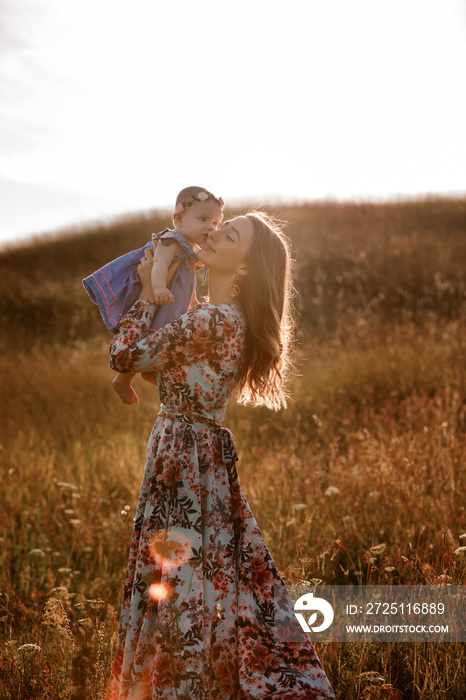 Beautiful woman is hugging her adorable baby girl. Happy parent spending time playing with daughter 