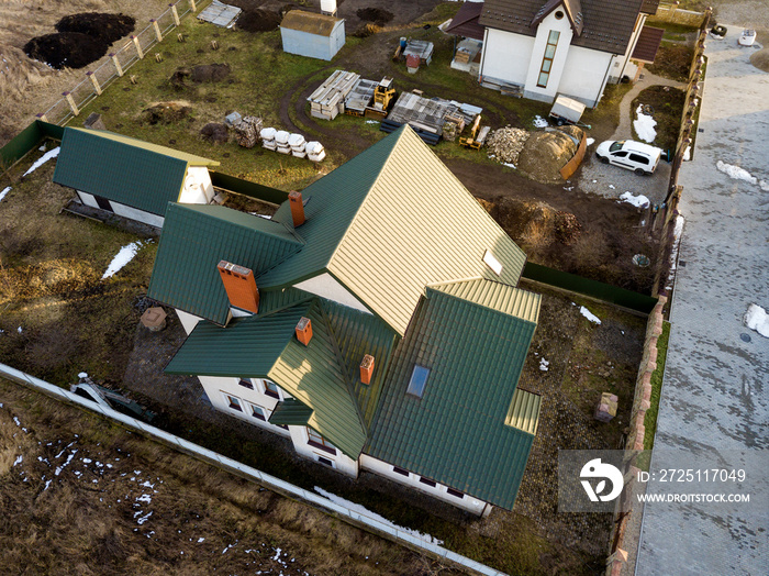 Aerial view of new residential house cottage and garage or barn with shingle roof on fenced yard on 