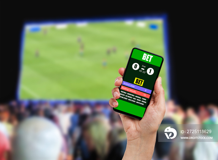 近距离拍摄一名男子在酒吧赢得一场足球比赛的在线投注时拿着手机。