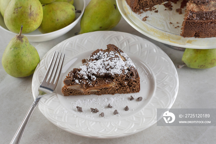 巧克力梨蛋糕放在撒有糖粉和巧克力的白色盘子上的俯视图