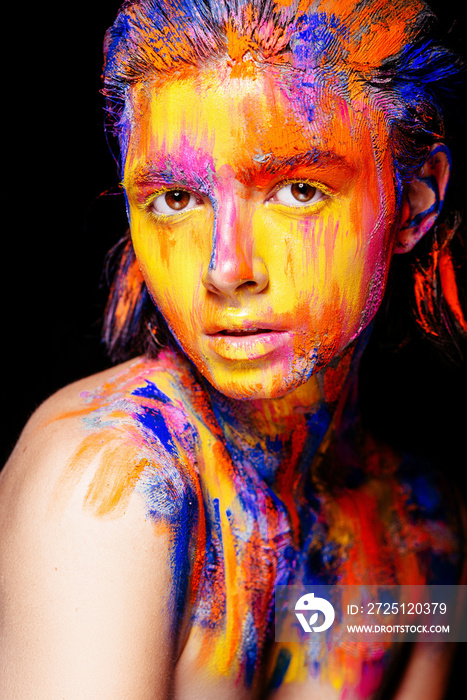 Art makeup. Face, neck and hair girls smeared with bright colors of yellow, blue and pink colors. Ho