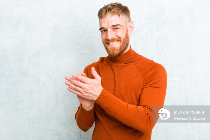 young red head man wearing turtle neck feeling happy and successful, smiling and clapping hands, say