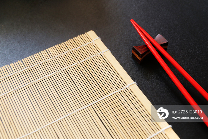黑色桌子上的红色筷子和竹垫俯视图，带复制空间
