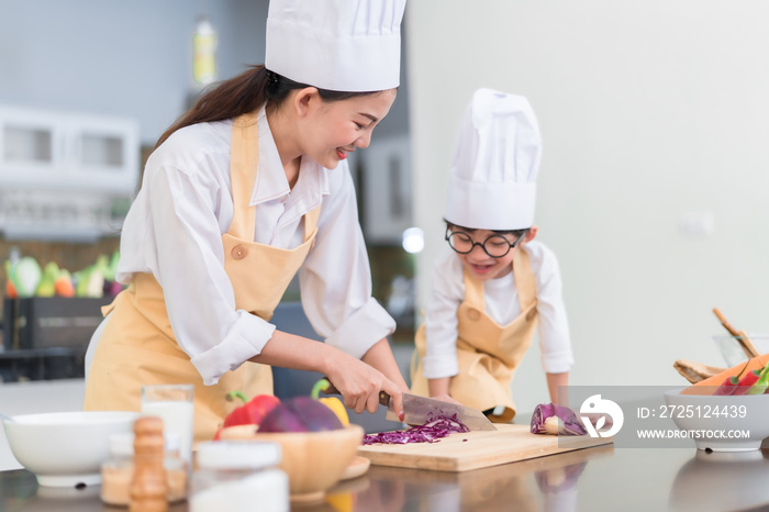 Professional Chef asian mom teaching little son cooking salad vegetable prepare healthy food in the 