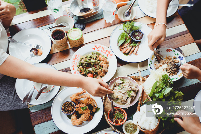 家庭聚会喜欢在乡村餐厅吃泰国菜。亚洲菜放在木桌后面