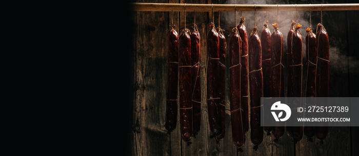 The process of smoking hanging sausages in the smokehouse. Clouds of smoke rise up and envelop the s