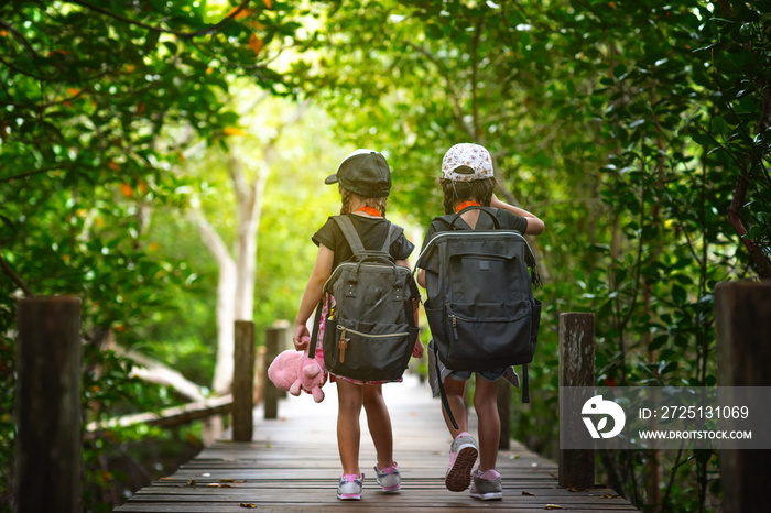 girls walking together on the wooden bridge of rainforest for learning and replenish kids experience