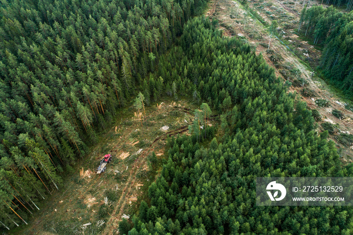 An aerial of a forwarder collecting freshly cut timber logs on a clear cut area in rural Estonia, No