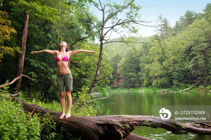 Woman standing on log by river