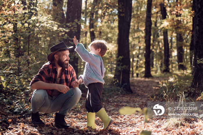 Brutal bearded man and little boy enjoy autumn nature. Family leisure. Family values. Explore nature