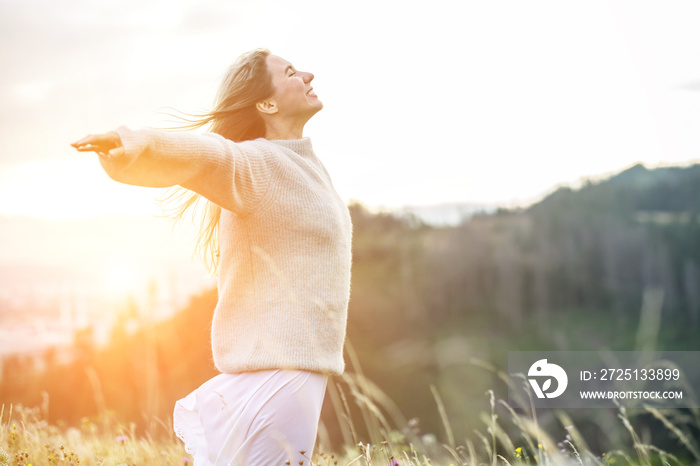 Happy woman enjoying sunset stay on the green grass on the forest peak of mountain. Fresh air, Trave