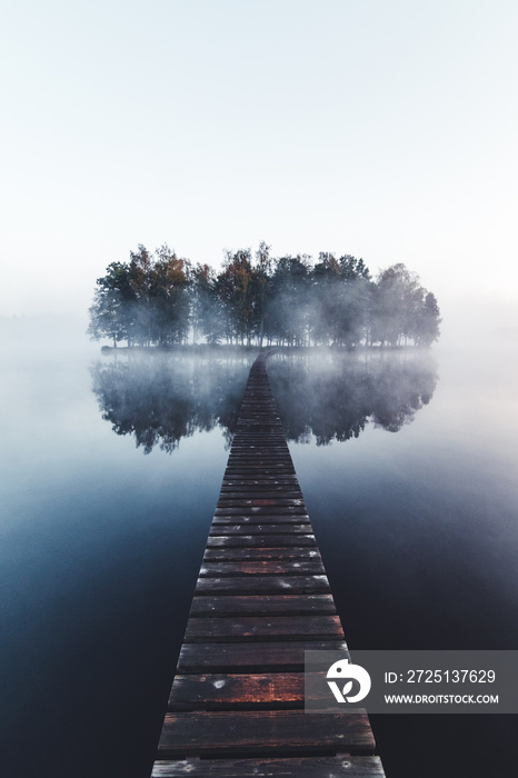 Wooden bridge on little island in fog