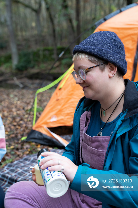 Woman drinking from insulated drink container while camping