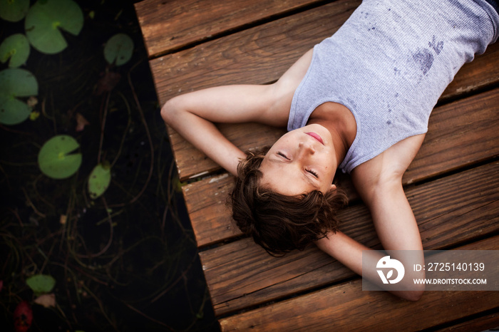 Overhead view of boy lying on wooden pier