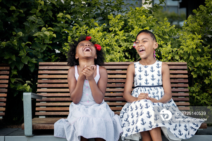 Girls laughing on bench outdoors