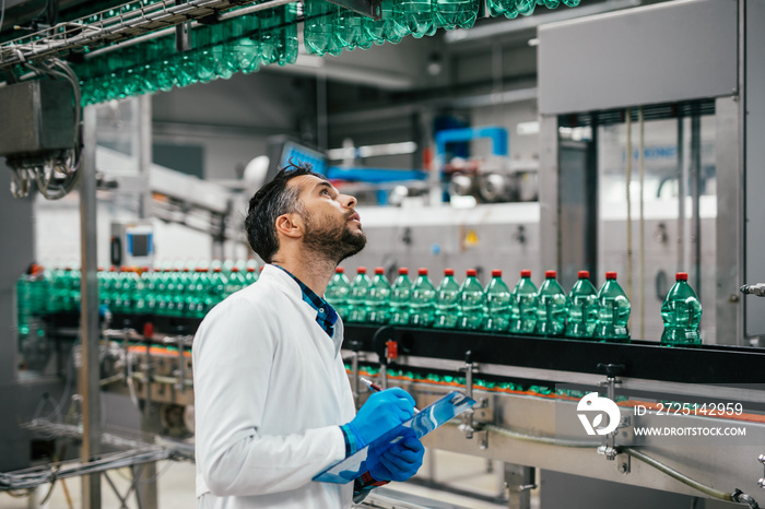 Male worker in bottling factory checking water ottles before shipment. Inspection quality control.