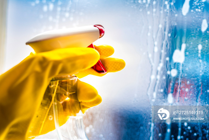 Cleaning window with squeegee with blue sky . Hand in yellow glove.