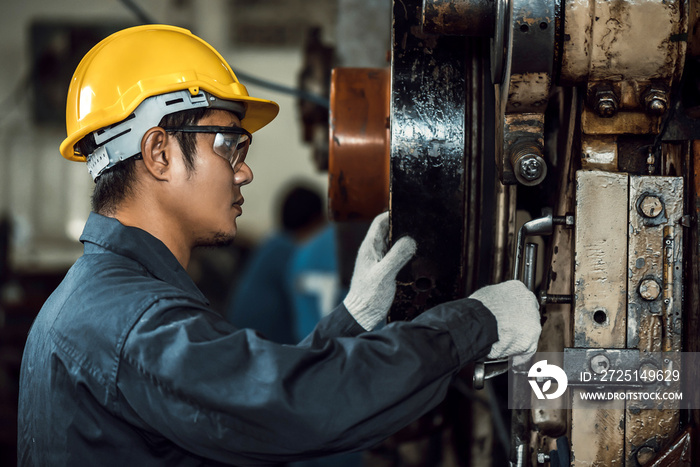 mechanic man checking and repair metal work pressing machine at factory.