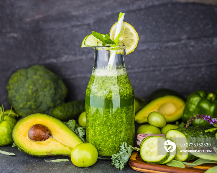 Healthy green smoothie in a glass bottle on dark stone background. Vegetarian food and detox diet.