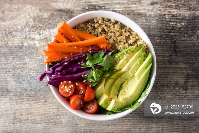 Vegan Buddha bowl with fresh raw vegetables and quinoa on wooden table. Top view