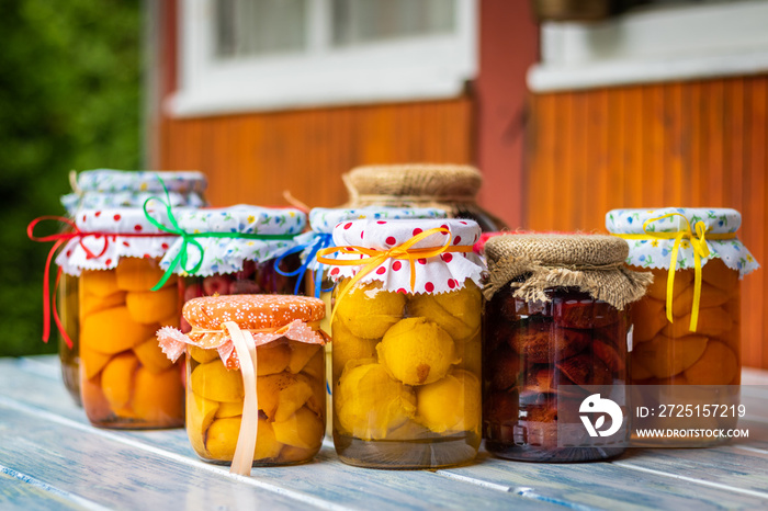 Homemade fruit compotes on table in garden, selective focus