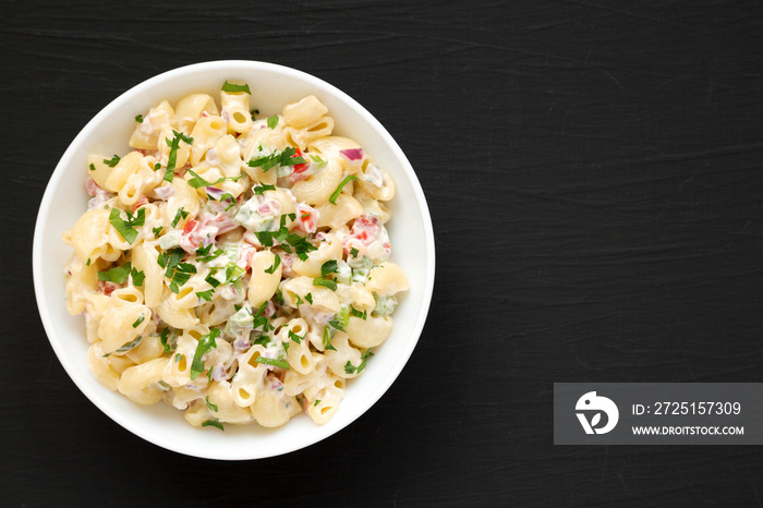 Homemade Macaroni Salad in a white bowl on a black surface, top view. Flat lay, overhead, from above