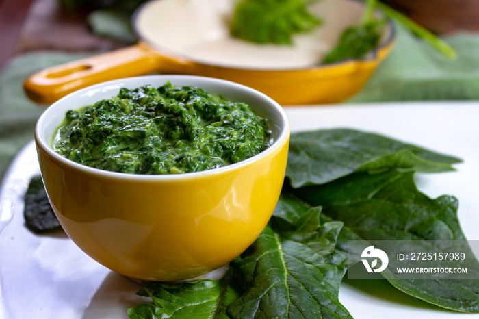 Healthy vegetarian or vegan food, cooked green spinach with cream, ingredient for many dishes like p