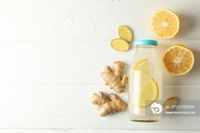 Bottle of ginger lemon water on white wooden background