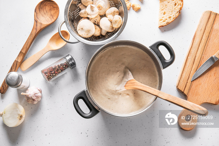 Pot with delicious mushroom cream soup on white table