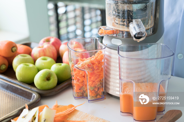 用食品榨汁机榨取健康的蔬菜和水果汁。女性榨取绿色和红色苹果果实