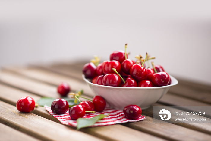 fresh cherries fruits in a white bowl on wooden table