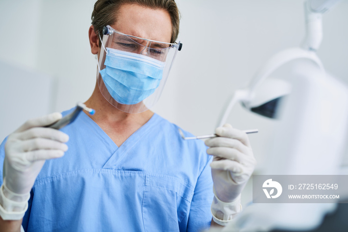 Confident dentist in protective mask preparing for dental procedure