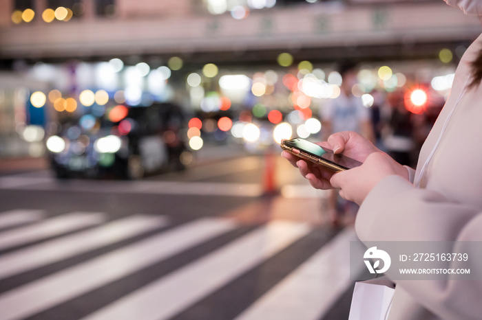 夜の渋谷でスマホを操作する若い女性の手元