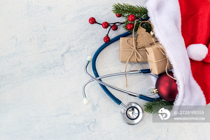 Santa Claus hat and stethoscope, Christmas gifts, and a branch of Christmas tree with red Christmas 