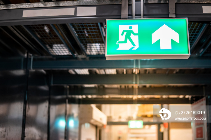 Green emergency exit sign or fire exit sign showing the way to escape with arrow symbol.