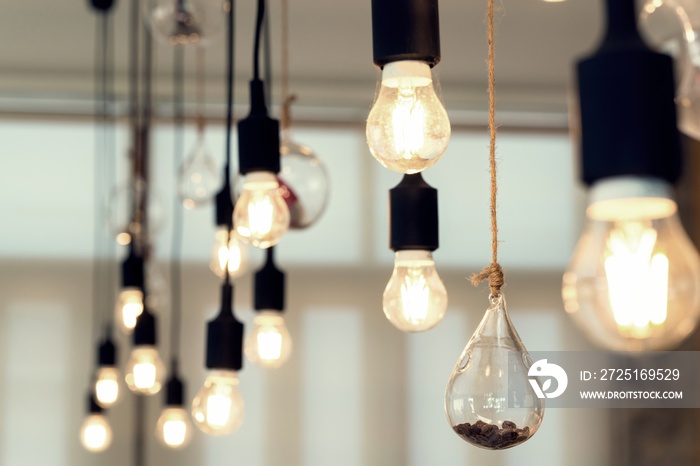 Old dusty hanging light bulb glowing and coffee beans in the bulb at the room.