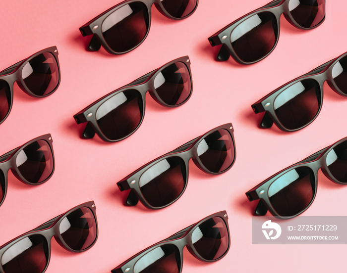 Pattern of sunglasses over a pastel pink background with copy space minimal concept